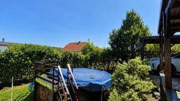 Un jardin avec un trampoline, une terrasse en bois et une voiture garée à proximité.
