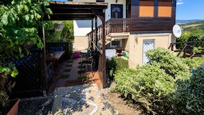 Ein zweistöckiges Haus mit Balkon, einer Sitzecke im Garten und einer Terrasse.