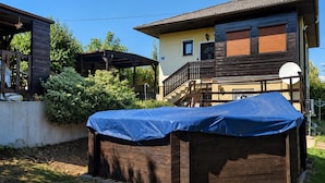 Ein zweistöckiges Haus mit überdachter Terrasse, Satellitenschüssel und Holzdeck.