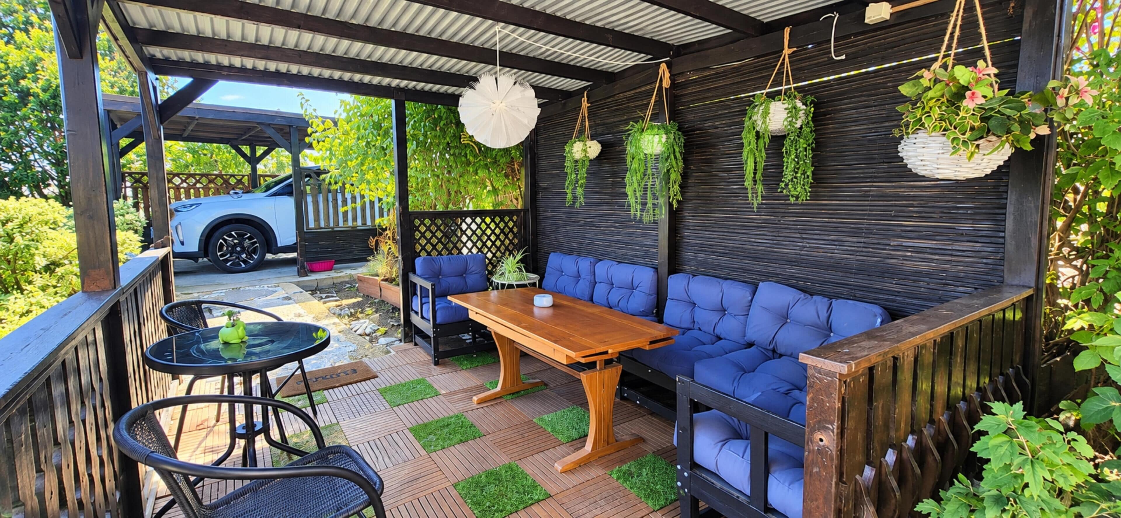 A covered outdoor seating area with a wooden table and blue cushioned seating.