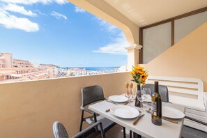 A balcony with a table set for two, overlooking a coastal cityscape. - Central 1 Bedroom Apartment. Communal Heated Pool (Los Cristianos)