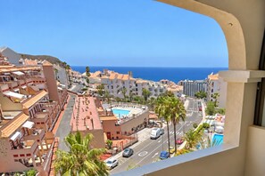 A coastal town with a view of the sea, buildings with balconies, and a swimming pool. - Central 1 Bedroom Apartment. Communal Heated Pool (Los Cristianos)