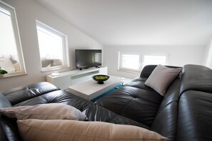 A modern living room with a leather sofa, a flat-screen TV, and a white coffee table. - Adriatic coast retreat - Apartment Antun #5 (Blace)
