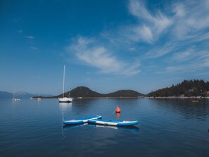 Ruhiges Wasser mit einem Segelboot, einem Stand-Up-Paddle und einer Boje.
