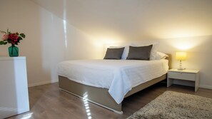 Une chambre à coucher avec un lit, des tables de chevet, une lampe et un vase rempli de fleurs.
