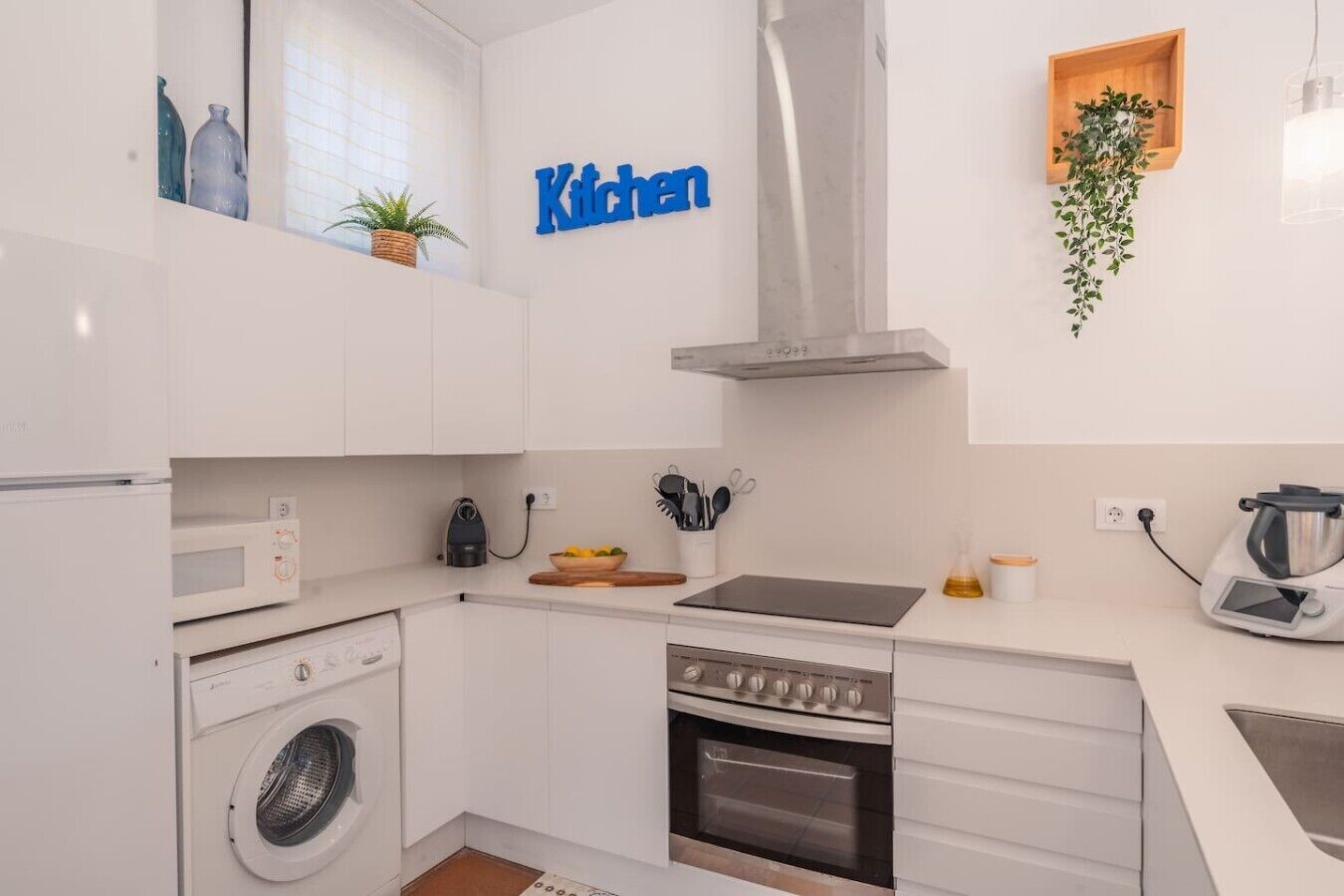 Cocina compacta con lavadora, horno, microondas y fregadero.