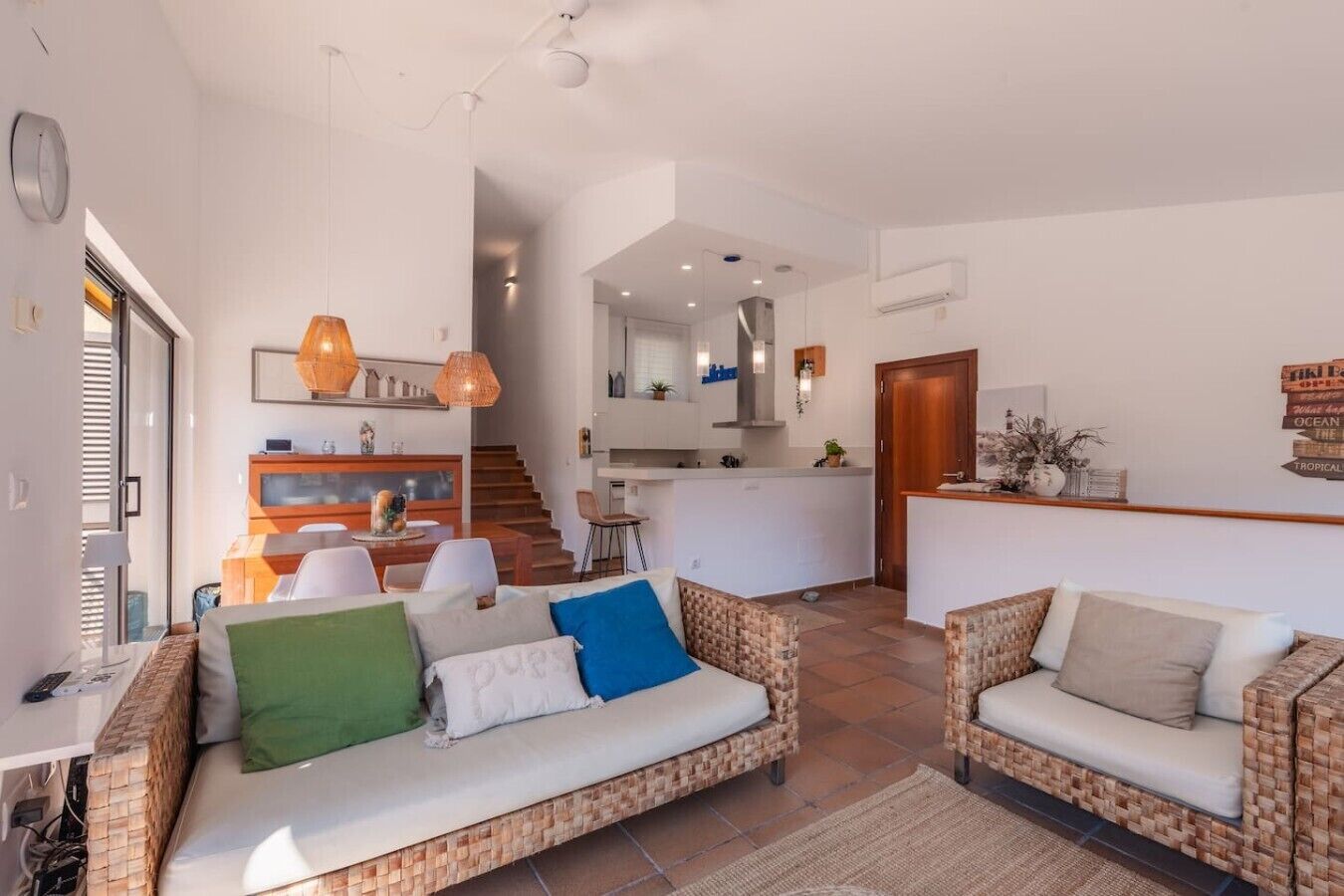 A modern living room with a sofa, a dining area, and a kitchen.