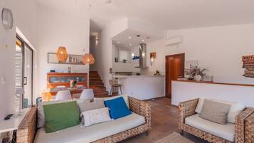 A modern living room with a sofa, a dining area, and a kitchen.