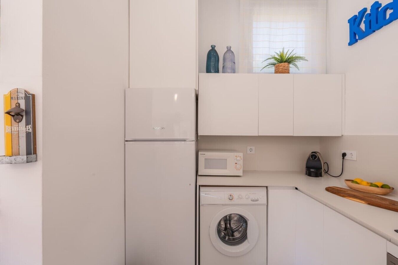 Una cucina compatta con frigorifero, microonde e lavatrice.