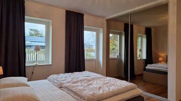 Ein Schlafzimmer mit einem Bett, einer Nachttischlampe, einem Fenster und einer Schiebetür, die auf einen Balkon führt.