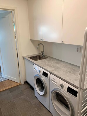 Ein kleiner Hauswirtschaftsraum mit Waschmaschine, Spüle und Schränken.