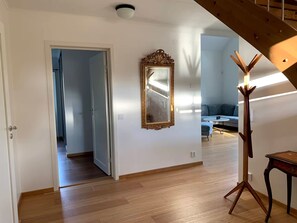 A room with a wooden floor, a mirror with an ornate frame, and a modern floor lamp.