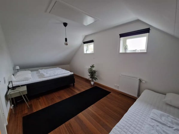 Ein Schlafzimmer mit einem Bett, einem Schreibtisch, einem Heizkörper und einem Fenster.