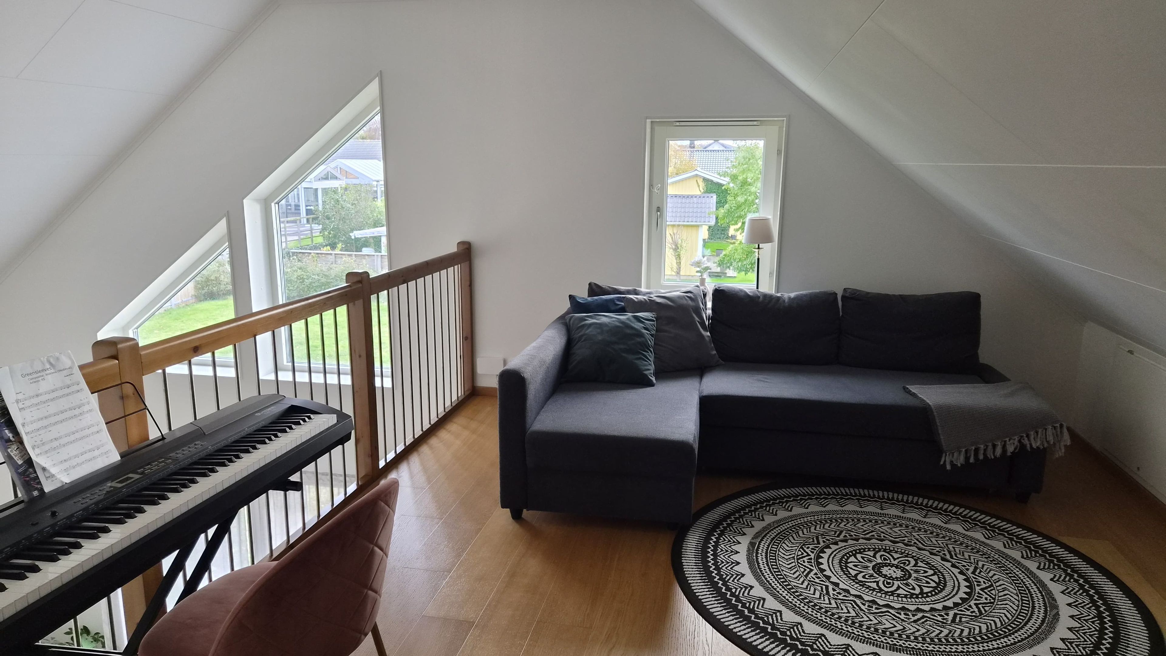 A loft-style room with a piano, a sofa, and a patterned rug.