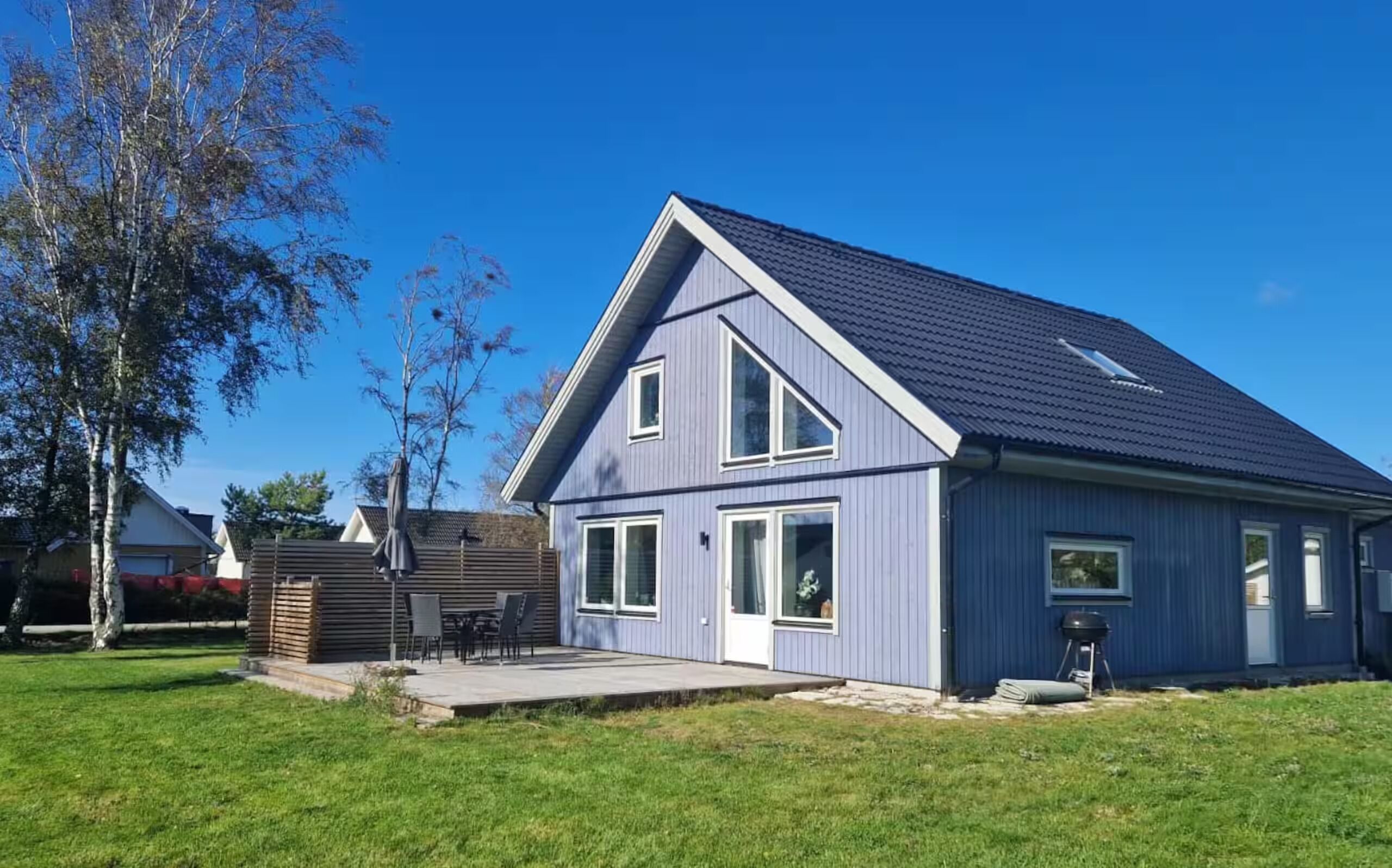 Ein modernes, zweistöckiges Haus mit einem geneigten Dach, einer überdachten Terrasse und einem gepflegten Rasen.