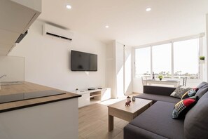 Una sala de estar moderna con un sofá, una mesa de centro y un televisor de pantalla plana montado en la pared.