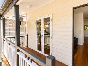 A residential property with a covered porch, a sliding glass door leading to a backyard, and a visible outdoor seating area. - Charming Queenslander 3 bed 1 bath in West End (West End)