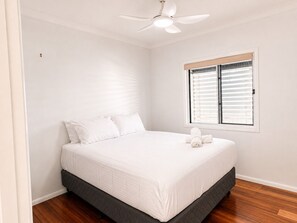 A bedroom with a bed, a ceiling fan, a window with blinds, and a wooden floor. - Charming Queenslander 3 bed 1 bath in West End (West End)