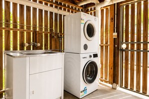 A laundry area with a washing machine and dryer, a sink, and a wooden fence. - Charming Queenslander 3 bed 1 bath in West End (West End)