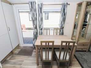 Ein Essbereich mit Holztisch und Stühlen, einer Schiebetür mit Vorhängen und Blick auf einen Balkon.