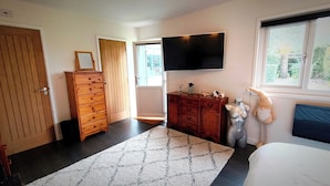 Une chambre à coucher avec un lit, une commode, un téléviseur et une fenêtre.