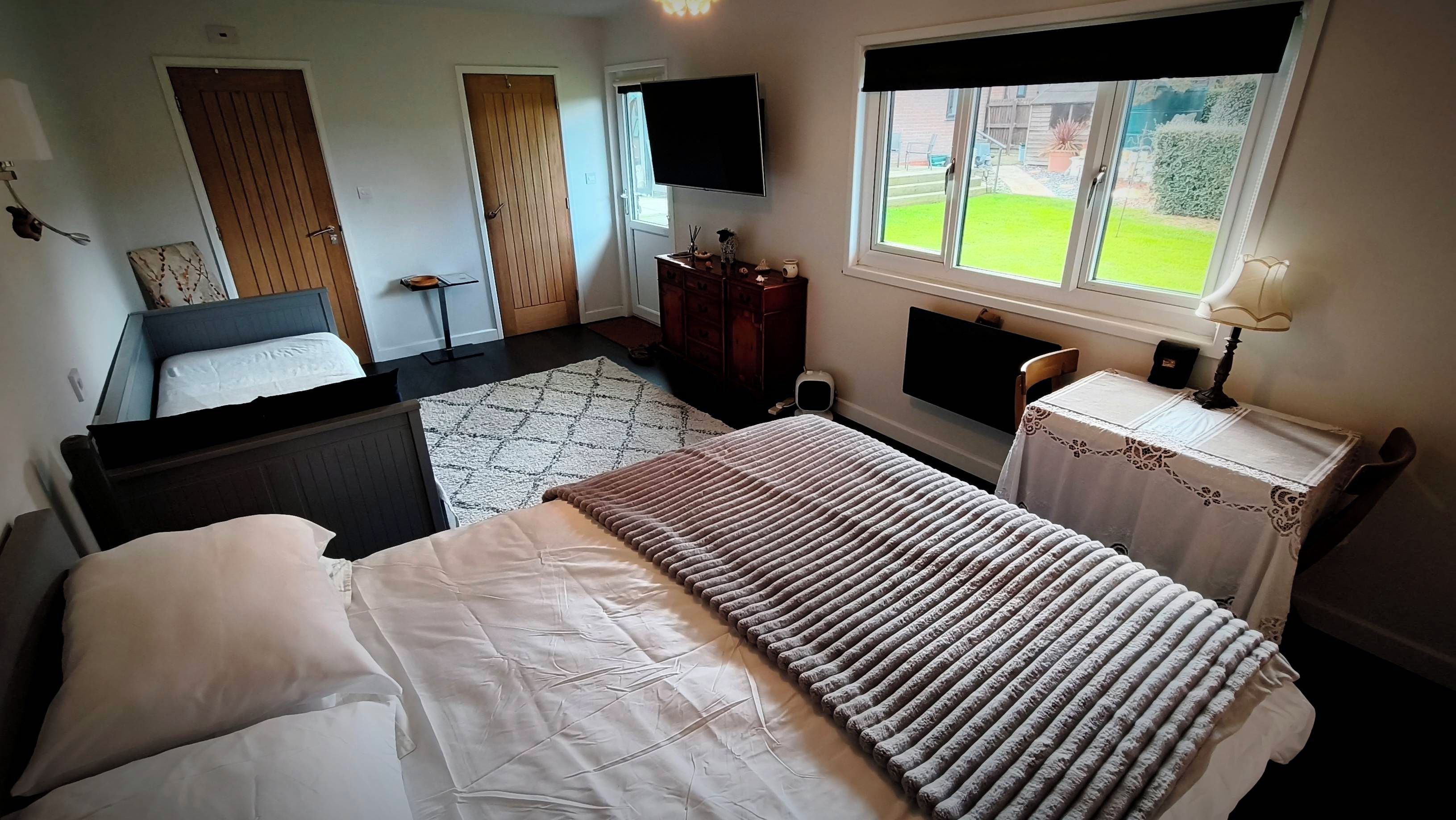 Quarto com cama, cômoda, televisão e janela com vista para o exterior.