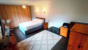 A bedroom with a bed, bedside table, dresser, and a rug.