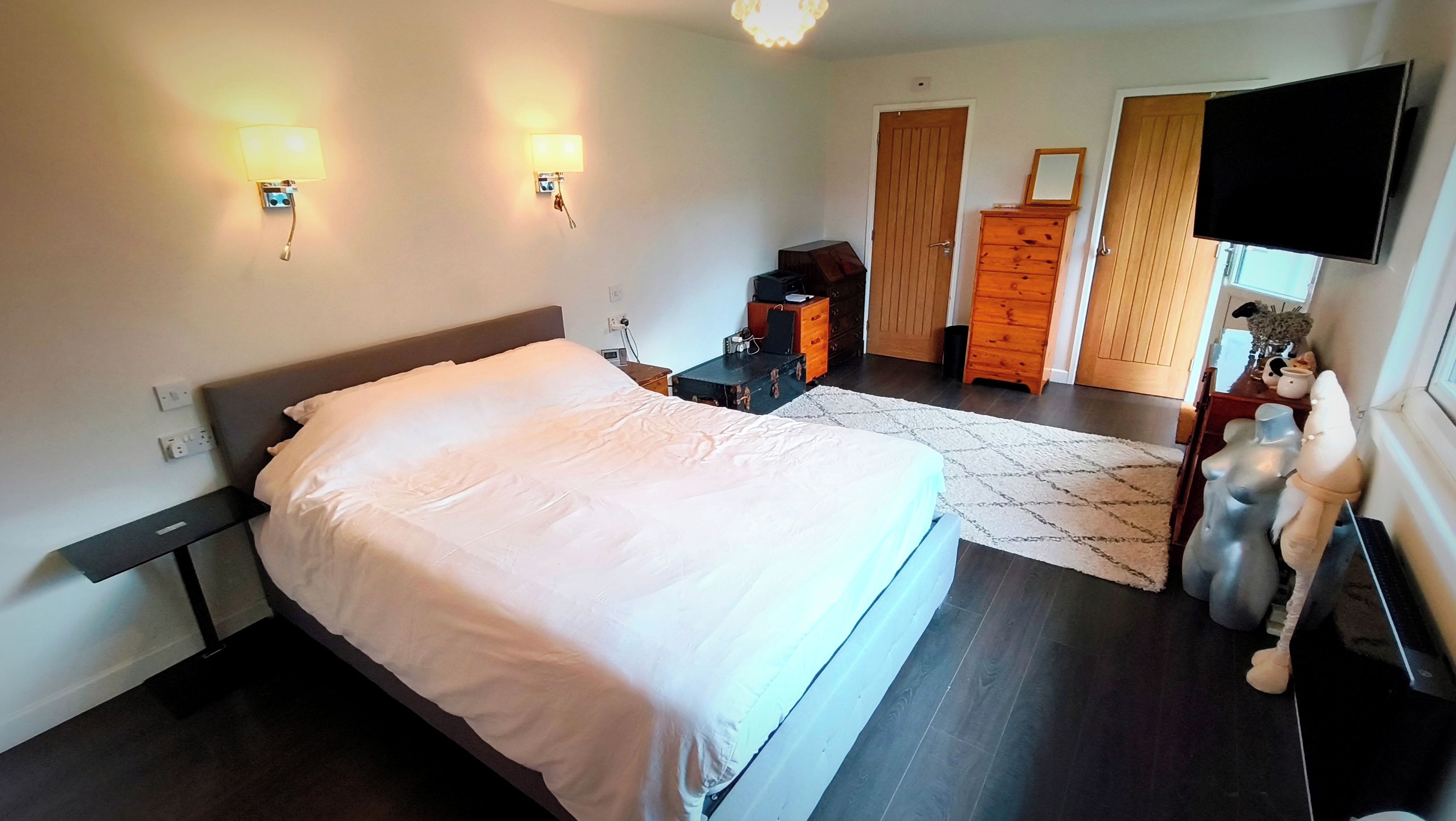 Ein Hotelzimmer mit einem großen Bett, Nachttischlampen, einem Schminktisch, einem Fernseher und einem Kleiderschrank.