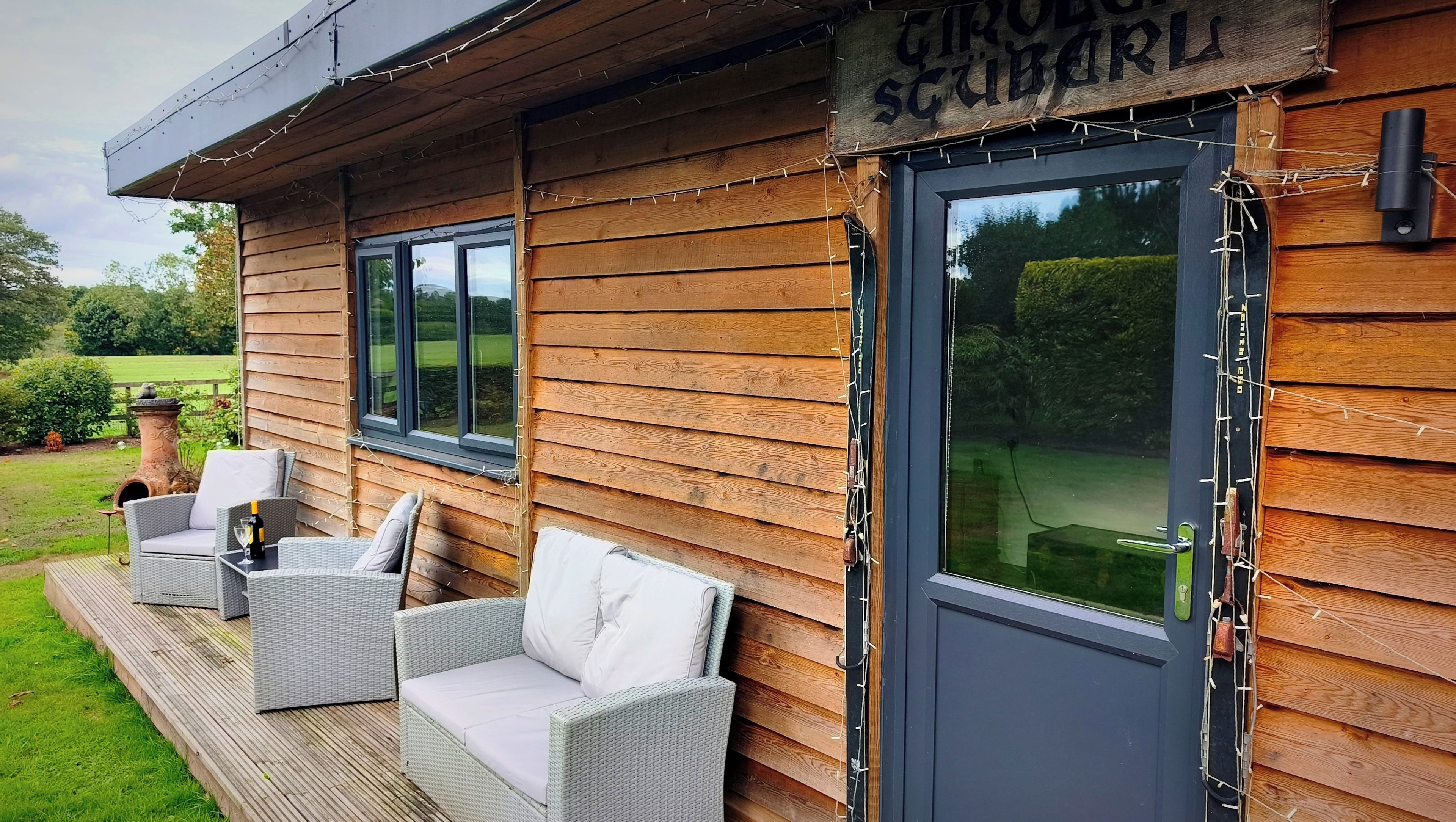 Une cabane en bois dotée d’une terrasse, de meubles en osier et d’une enseigne sur laquelle on peut lire : « CIRROBER SCHUBERL ».