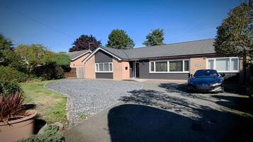A residential property with a driveway, a parked car, and a well-maintained lawn.