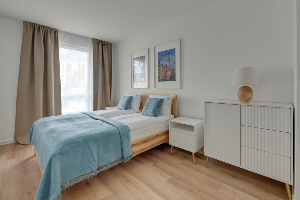 A bedroom with a bed, bedside tables, a dresser, and artwork on the wall.