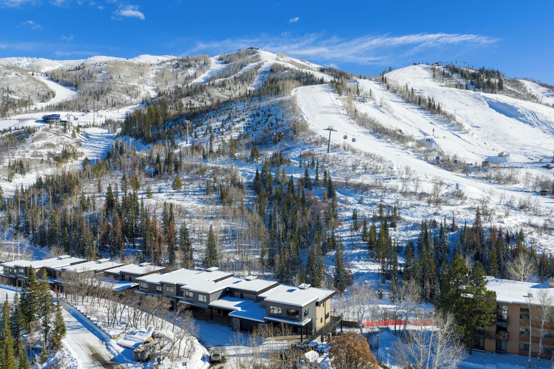 A ski resort with snow-covered slopes, a building with multiple floors, and a clear blue sky.