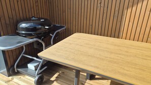 Une terrasse en bois avec une table et un barbecue.