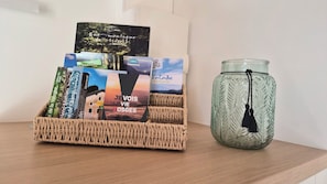 A woven basket with travel brochures and a glass candle with a tassel. - Cozy cabin-style chalet, comfort suite, hanging hammock, private spa, and air conditioning (Les Poulières)
