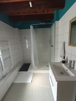 Ein Badezimmer mit Dusche, Waschbecken und weißen Fliesenwänden.