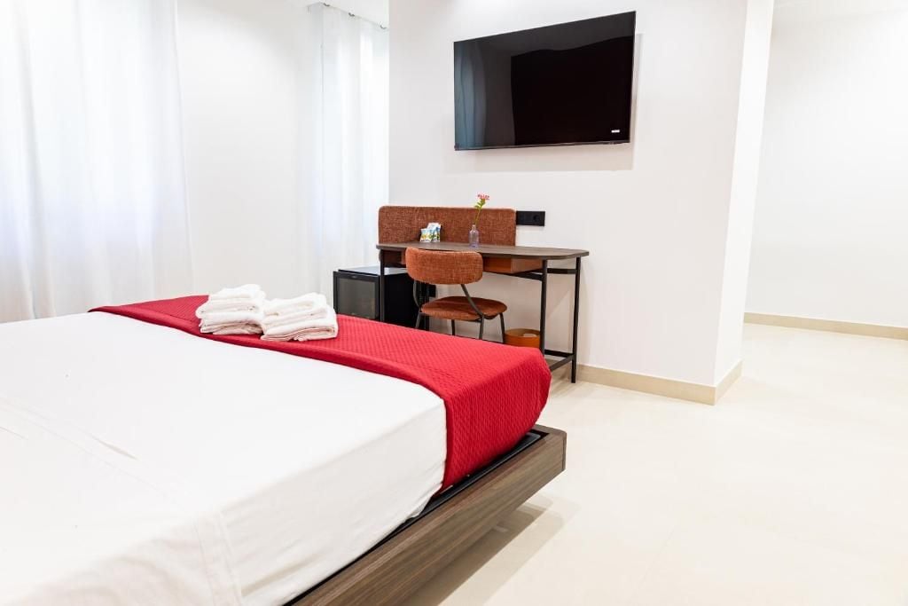 Una habitación de hotel con cama, escritorio y televisor.