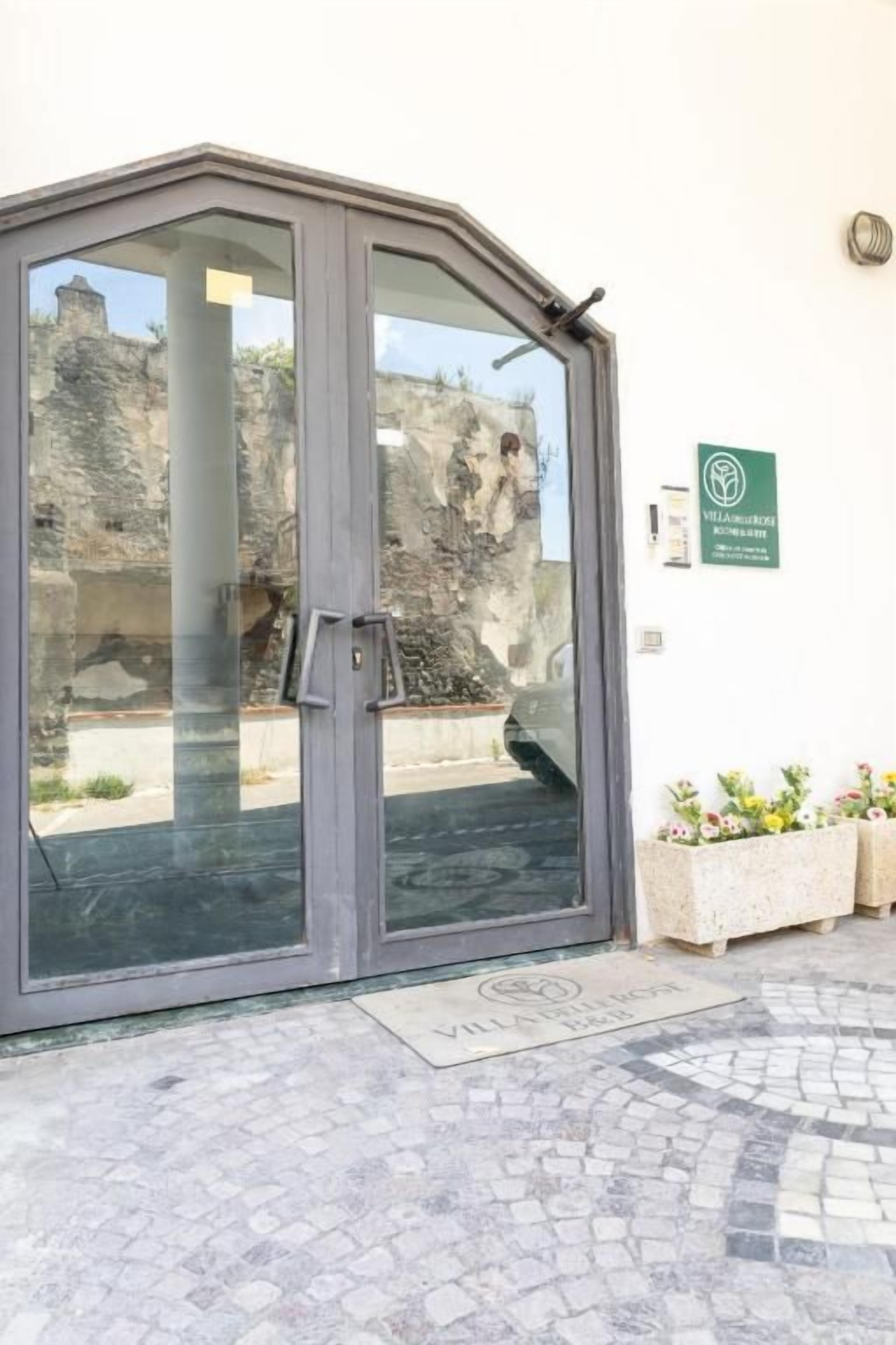 A glass door entrance with a metal handle, a green sign with a logo, and a tiled floor.