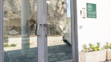 A glass door entrance with a metal handle, a green sign with a logo, and a tiled floor.