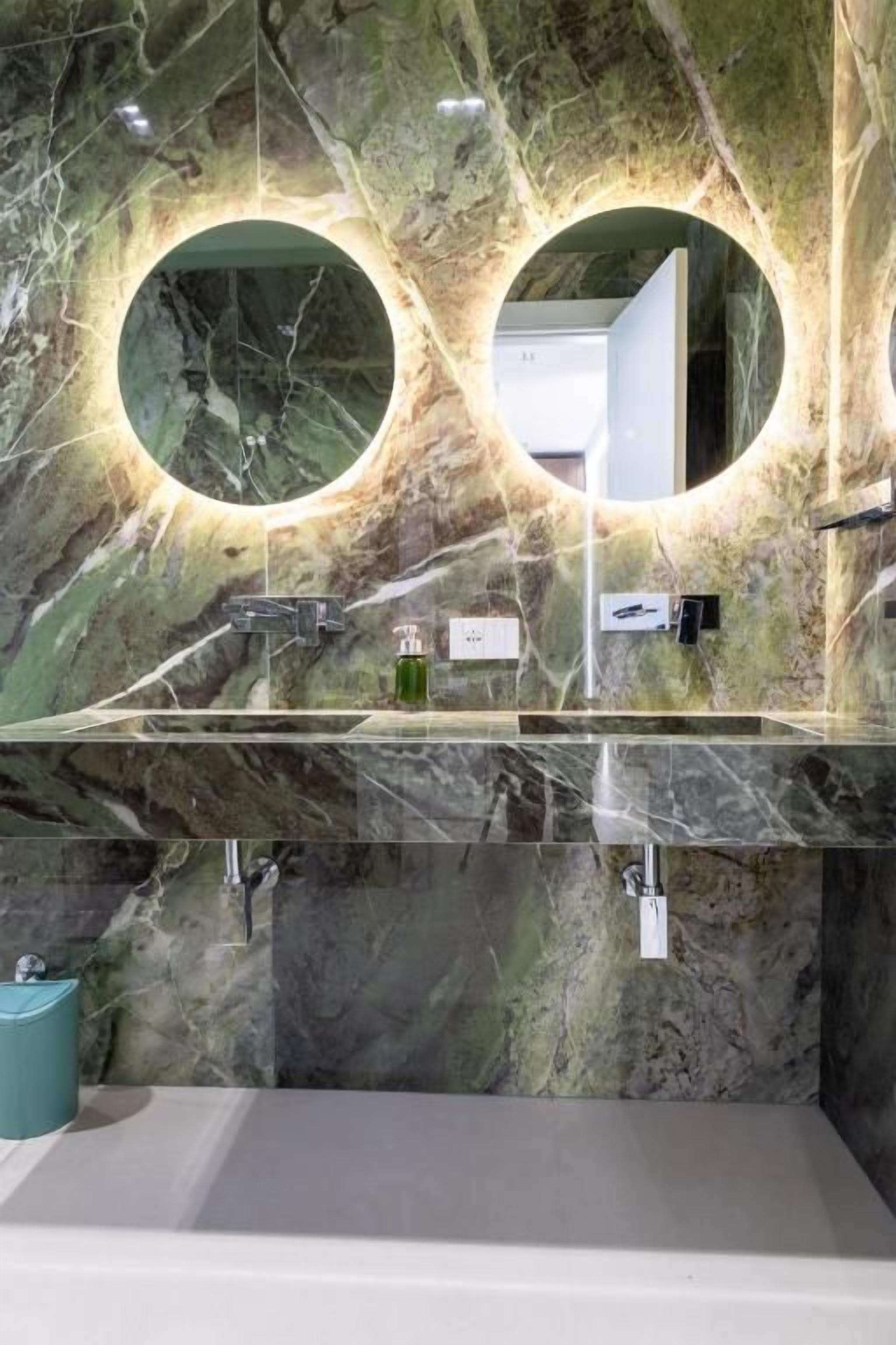 A bathroom with two circular mirrors, a marble countertop, and a white sink.