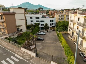 A residential area with multi-story buildings, a parking lot, and a mountain in the background. - Villa delle Rose Pompei Room and Suite (Pompei)