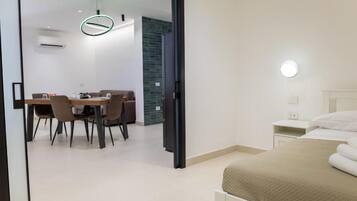 Et moderne hotelværelse med seng, natbord og spiseplads med stole og bord.