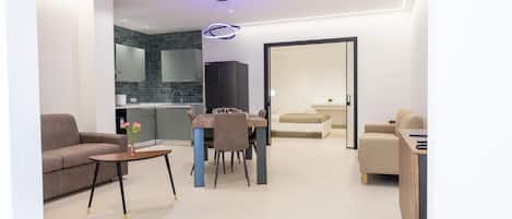 Una sala moderna con un sofá, una mesa de centro y un comedor con mesa y sillas.