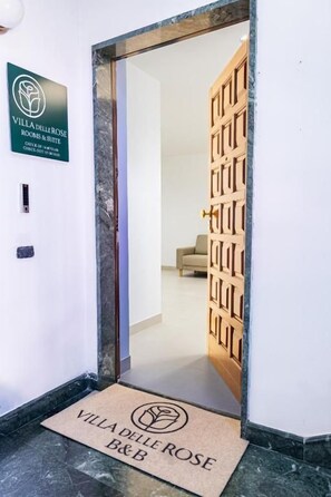 A hotel entrance with a wooden door and a doormat. - Villa delle Rose Pompei Room and Suite (Pompei)