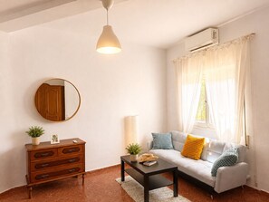 A living room with a sofa, a coffee table, a dresser, a mirror, and a hanging light fixture. - Villa Juanita – Andalusian charm near Torrecilla Beach, Nerja (Nerja)