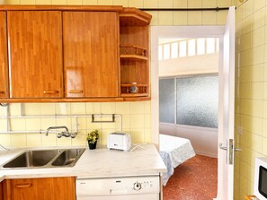 Eine kleine Küche mit Holzschränken, einer Spüle, einem Toaster und einem Geschirrspüler.