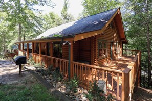 Une cabane en bois avec une véranda, un barbecue et un chemin pavé de pierres.
