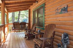 Eine Holzhütte mit Veranda, ausgestattet mit zwei Holzstühlen und einem Tisch.