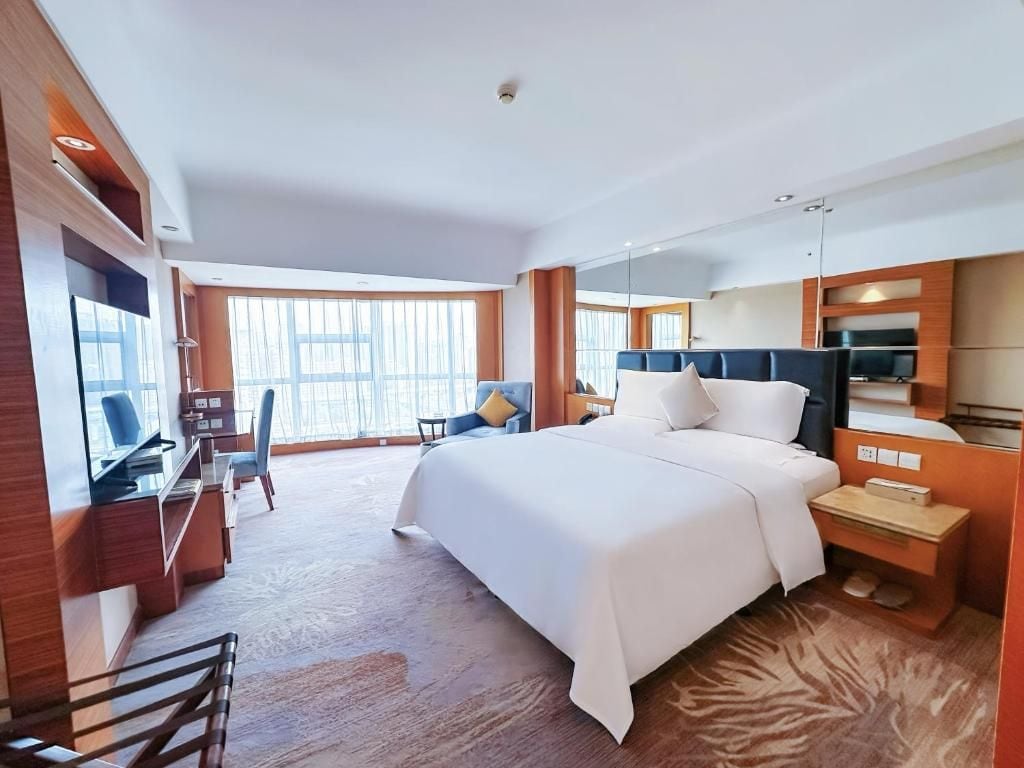 Habitación de hotel con una cama grande, un escritorio, una silla y un televisor.