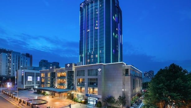 A modern hotel with a prominent tower, multiple entry points, and a well-lit parking area. - Empark Grand Hotel Xi'an (Xi'an)