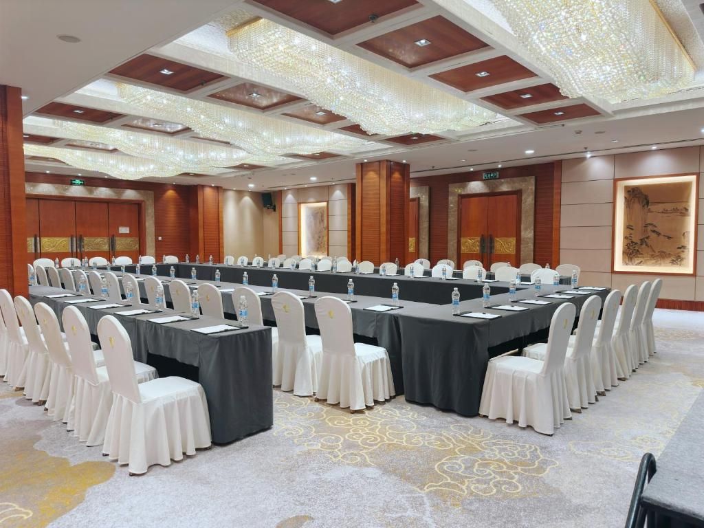 A conference room with a long table, white chairs, and a chandelier.